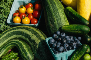 Green kale, spinach, zucchini, and cucumber with yellow summer squash, yellow and red cherry tomatoes, and blueberries