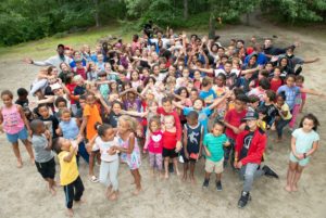 Large group of children in summer clothes with many different shades of skin pose for an aerial picture 