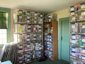 Shelves of neatly organized and labeled crafts line the walls of a small room