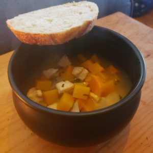 bowl of colorful stew in a black bowl with a slice of bread on the rim