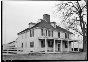 White two-storey house with a pyramidal roof, big chimney, and front porch