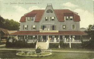 Postcard of a three-storey shingled building with people dotted along the wide front porch. Marked "Saunders House, Saunderstown, R.I."